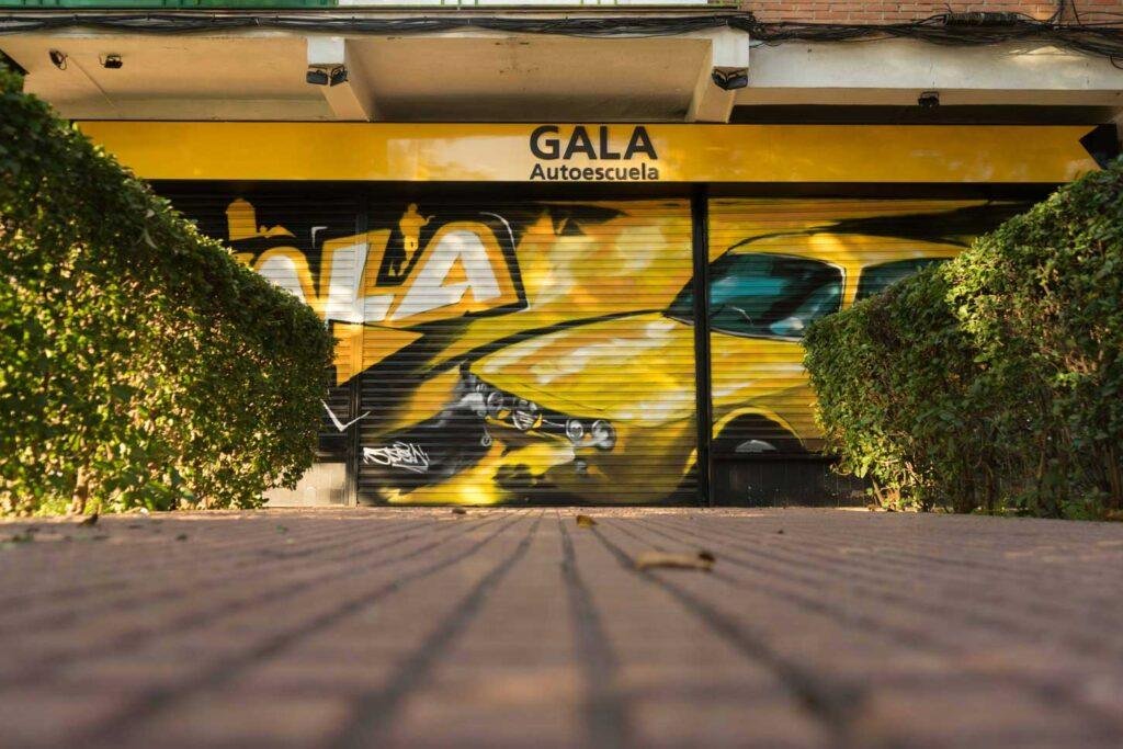 Cierre con mural de Rolls-Royce amarillo para Autoescuela Gala en estilo graffiti