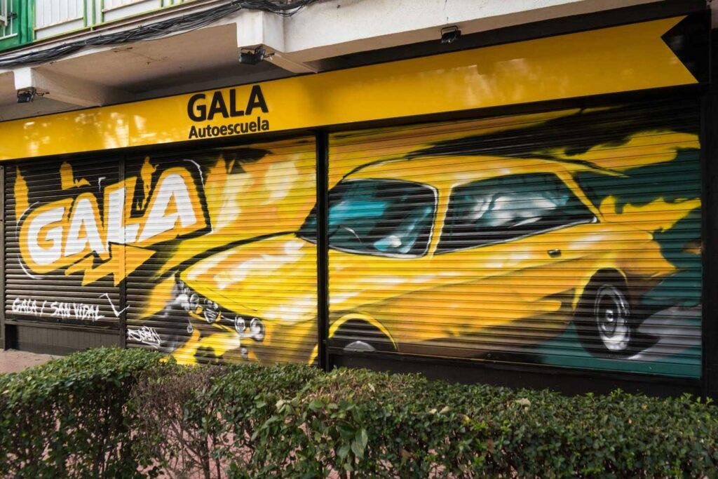 Cierre con mural de Rolls-Royce amarillo para Autoescuela Gala en estilo graffiti