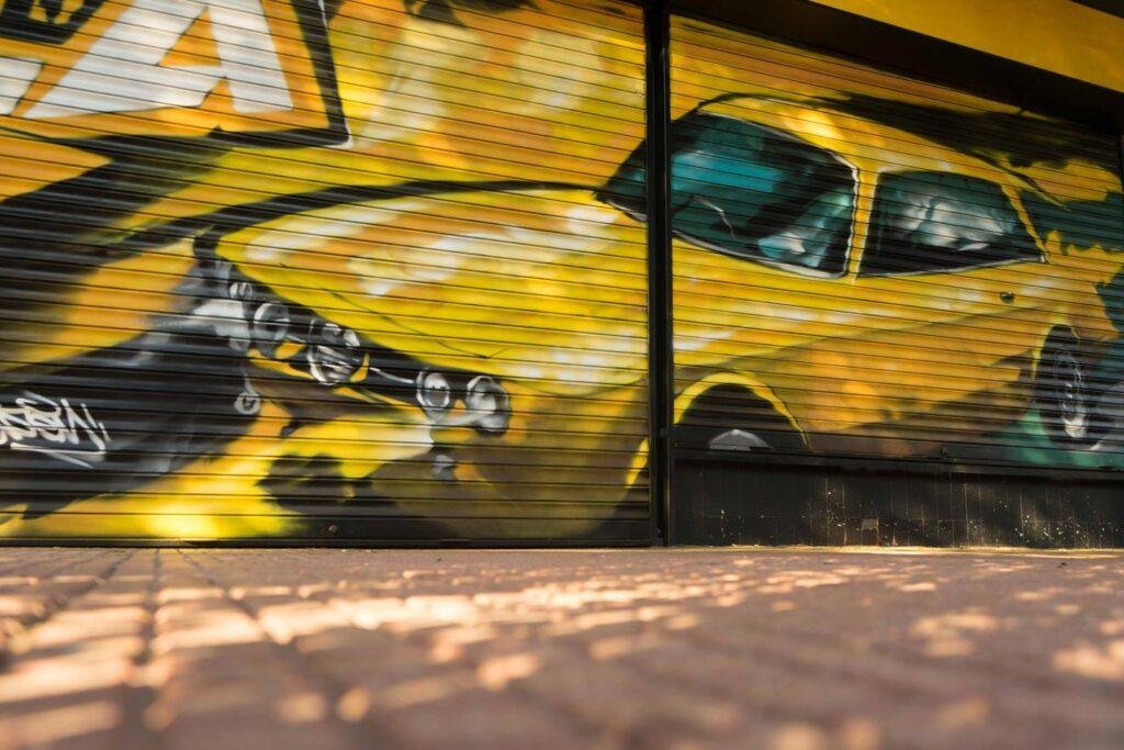 Cierre con mural de Rolls-Royce amarillo para Autoescuela Gala en estilo graffiti