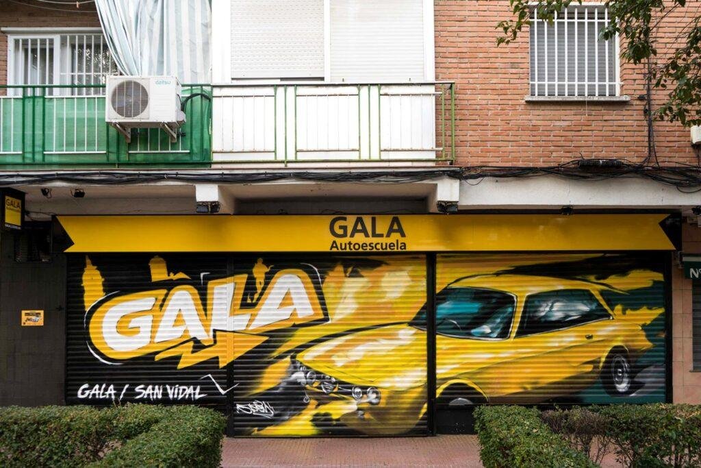 Cierre con mural de Rolls-Royce amarillo para Autoescuela Gala en estilo graffiti