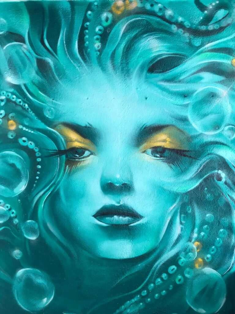 Mural urbano con rostro femenino turquesa en terraza interior