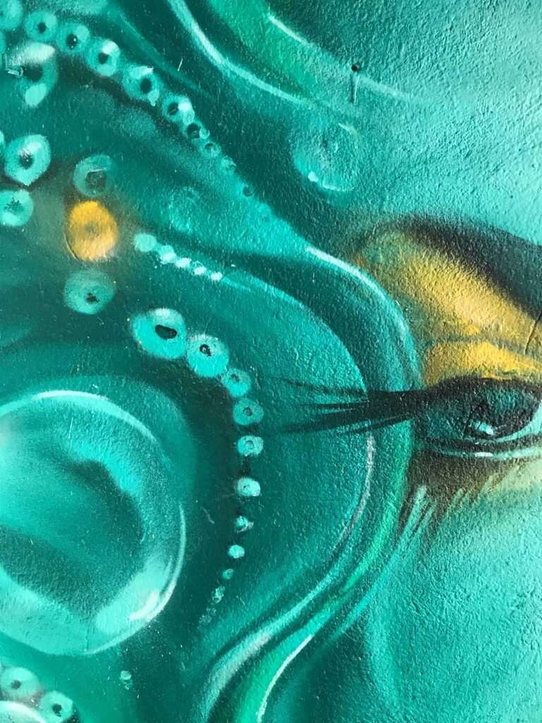 Mural urbano con rostro femenino turquesa en terraza interior