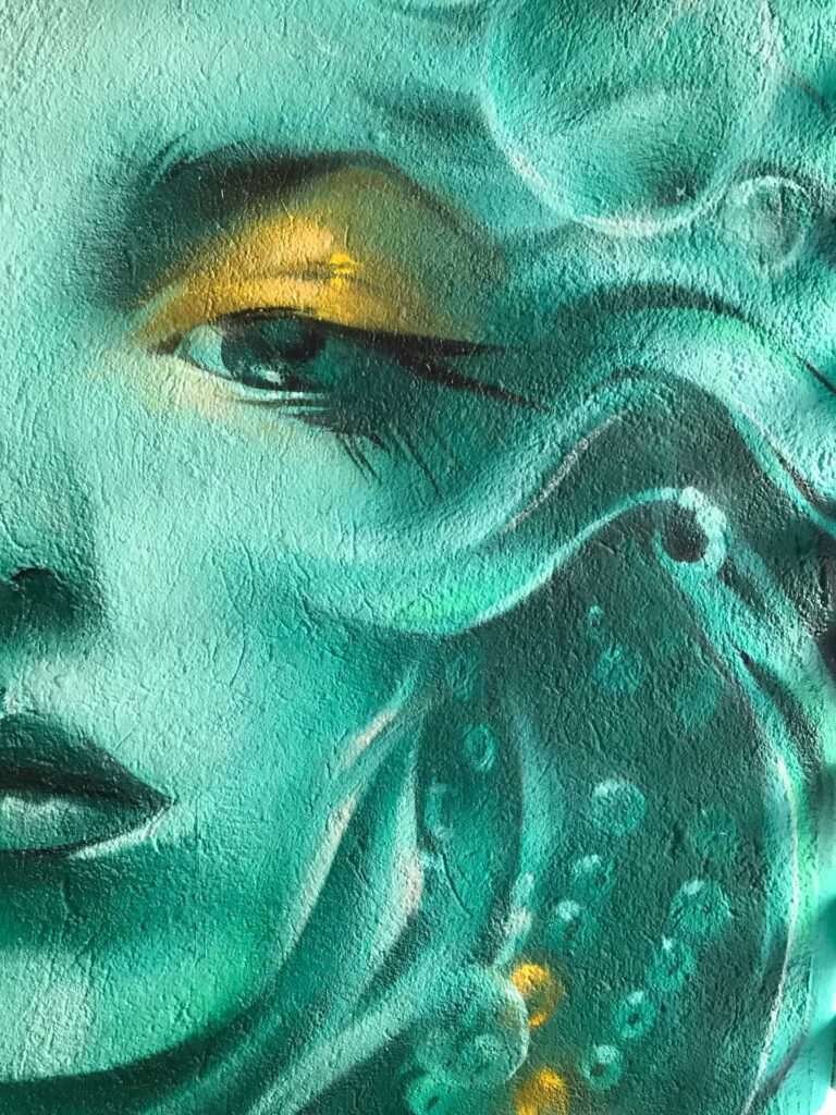 Mural urbano con rostro femenino turquesa en terraza interior