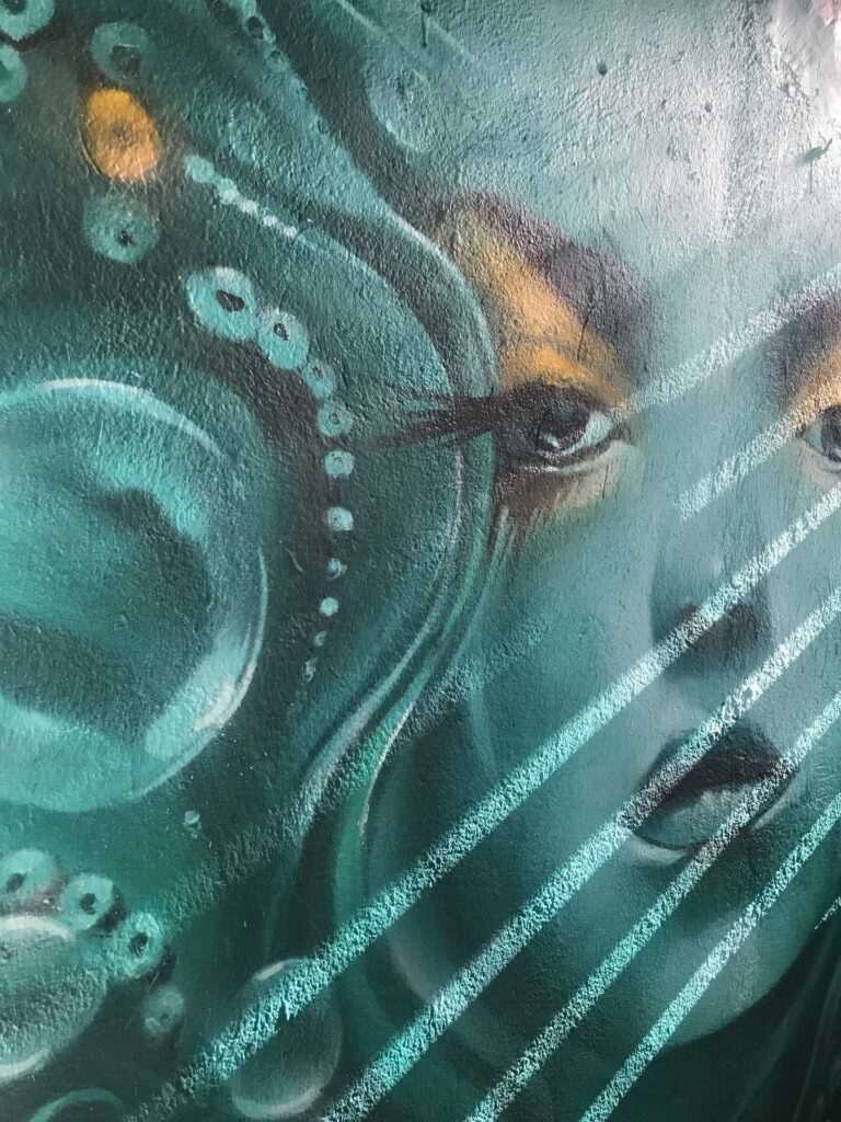 Mural urbano con rostro femenino turquesa en terraza interior