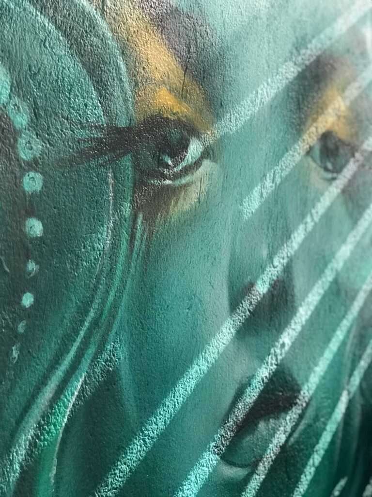 Mural urbano con rostro femenino turquesa en terraza interior