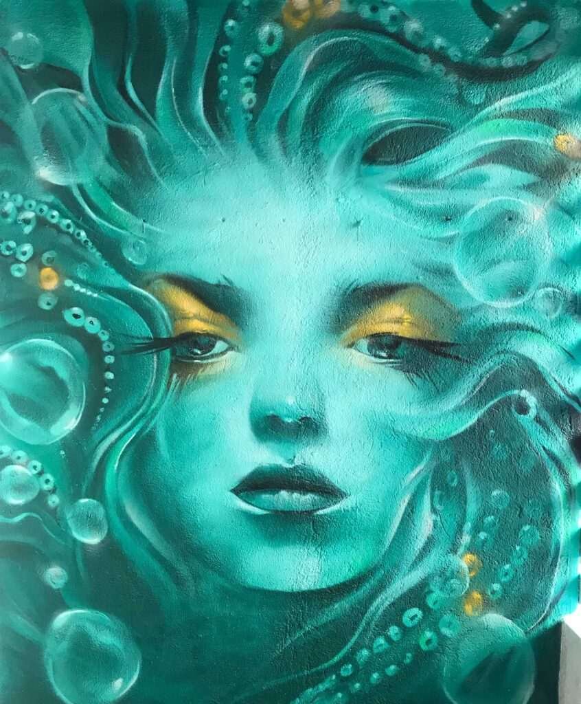 Mural urbano con rostro femenino turquesa en terraza interior