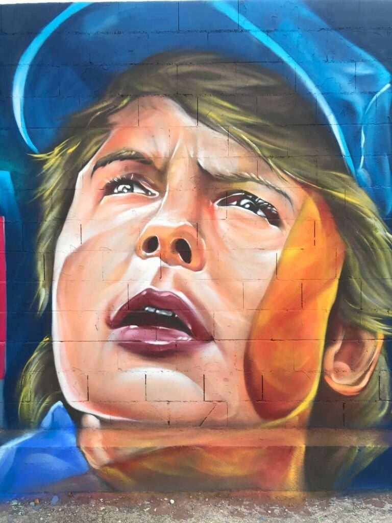 Mural graffiti de Marty McFly y el Delorean de Back to the Future con colores vivos y estilo ochentero