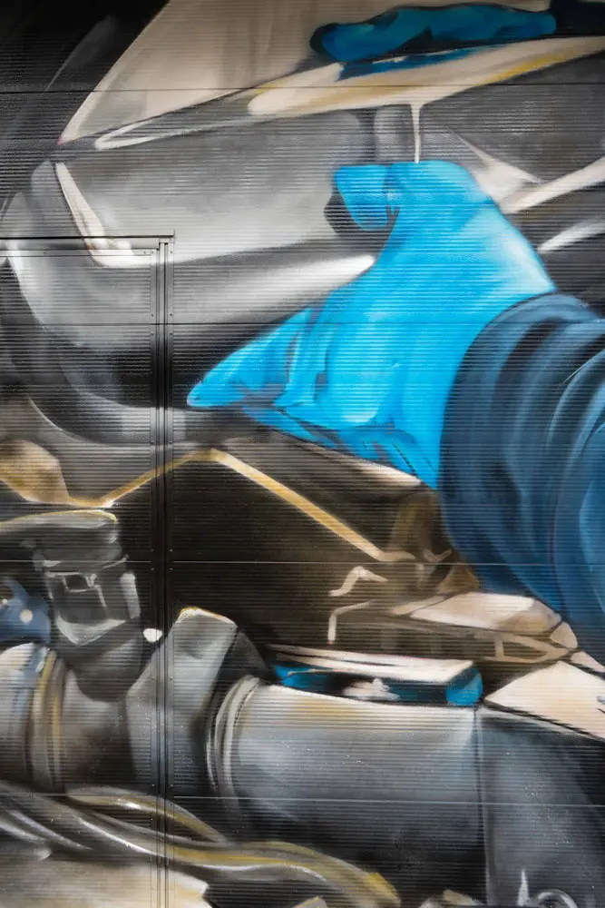 Mural mecánico realista en taller Euromaster Usera con motor y ruedas