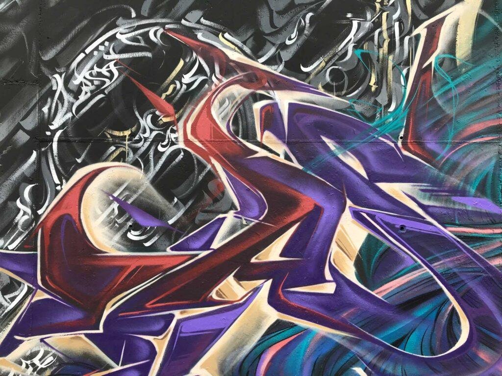 Lettering en morados y granates del mural Wild Beauty en un instituto de Madrid