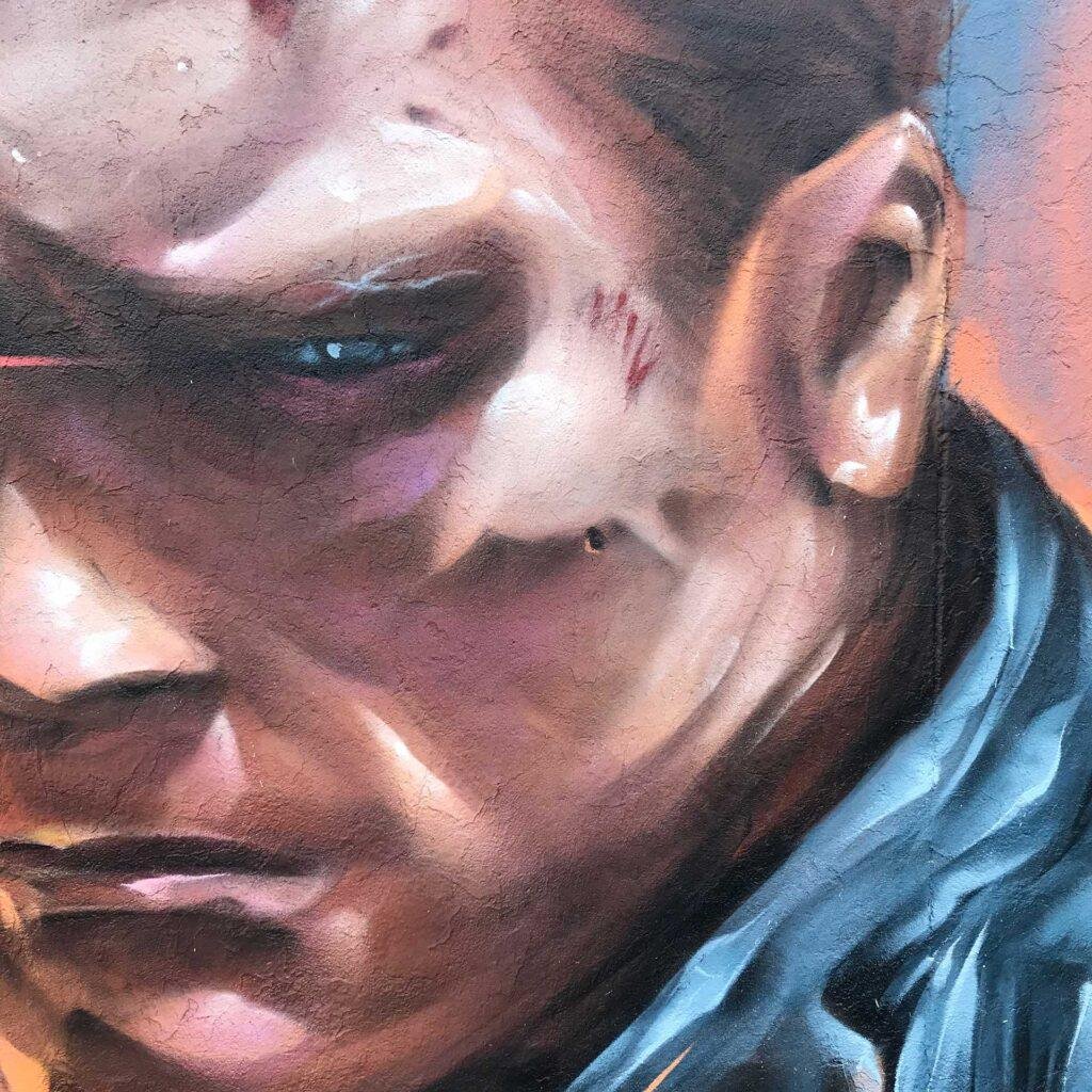 Graffiti hiperrealista de Terminator sobre fondo naranja y azul