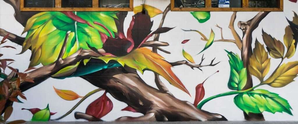 Mural con ramas y hojas en fachada de Farmacia Parque9, graffiti para imagen de salud