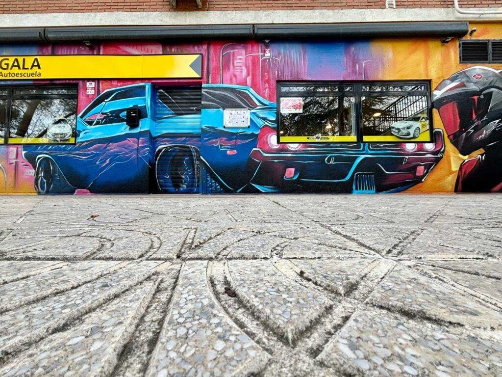 Vista lateral del mural para GALA Autoescuela en Móstoles con fachada completa y temática de motor