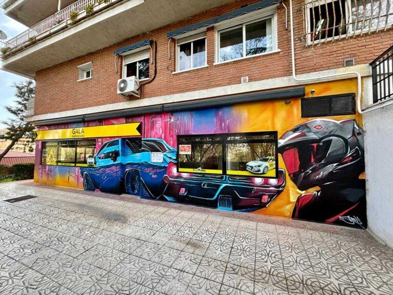 Mural en fachada de GALA Autoescuela Móstoles con coches deportivos, moto y colores urbanos