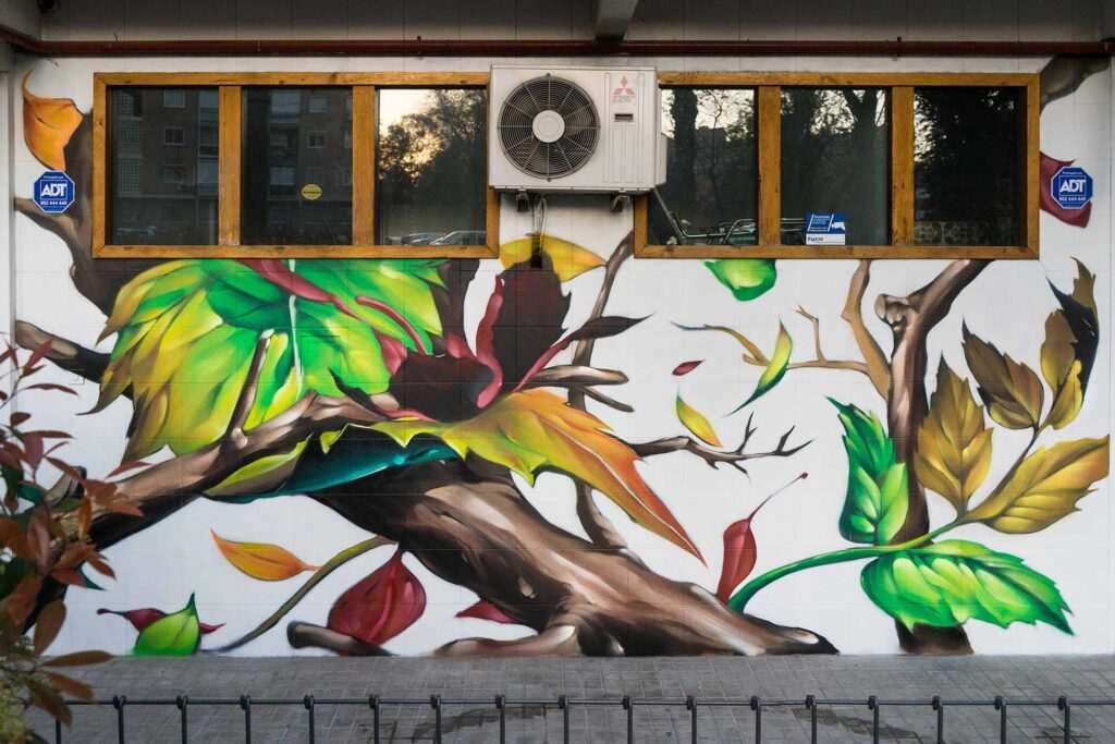 Mural con ramas y hojas en fachada de Farmacia Parque9, graffiti para imagen de salud