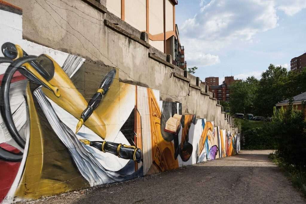 Vista exterior obra "Aprendizaje" con skyline Madrid · mural IES Isaac Newton · Asem Navarro · El Arte Urbano
