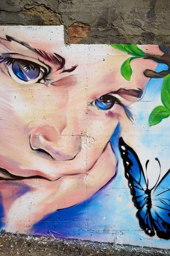 Detalle retrato infantil obra "Aprendizaje" · rostro niño con mariposa azul · mural IES Isaac Newton Madrid · El Arte Urbano