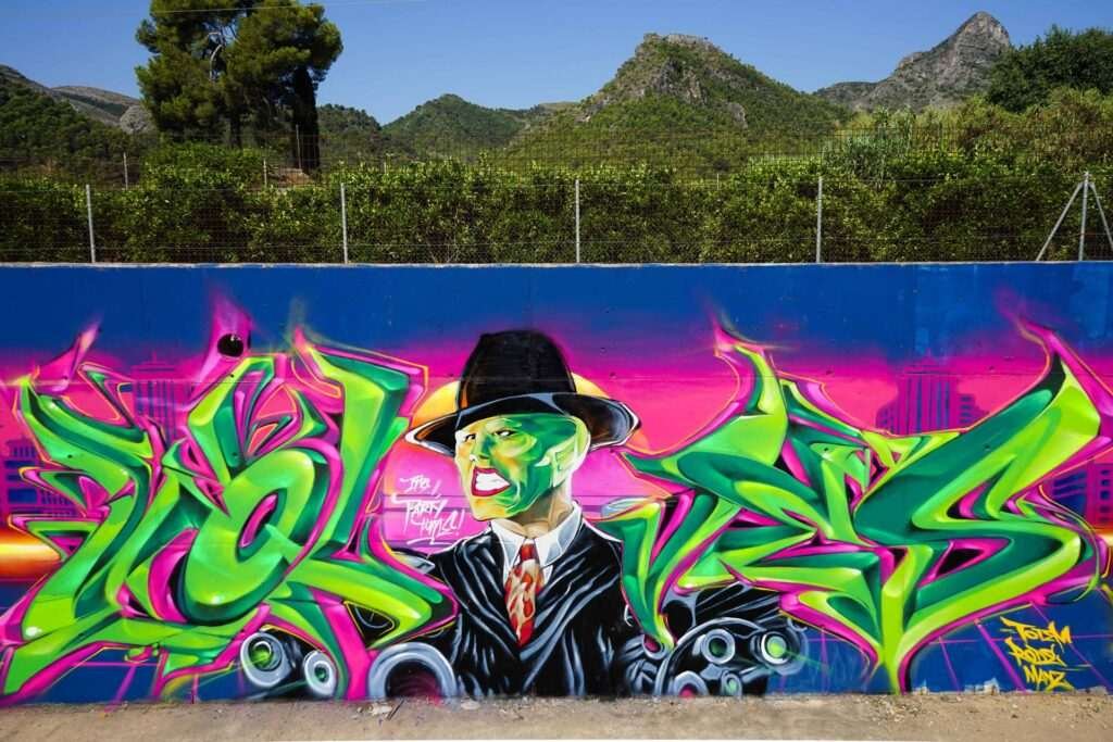 Mural de La Máscara estilo graffiti con fondo rosa y verde