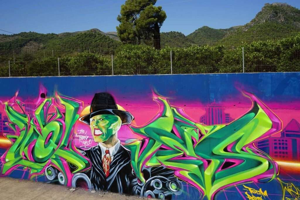 Mural de La Máscara estilo graffiti con fondo rosa y verde
