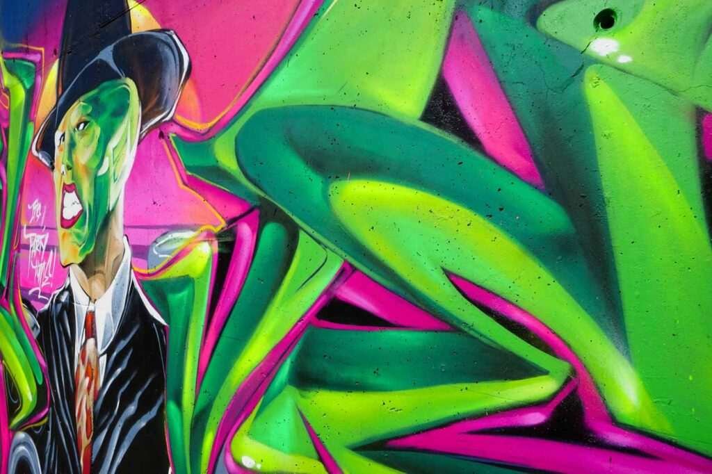 Mural de La Máscara estilo graffiti con fondo rosa y verde