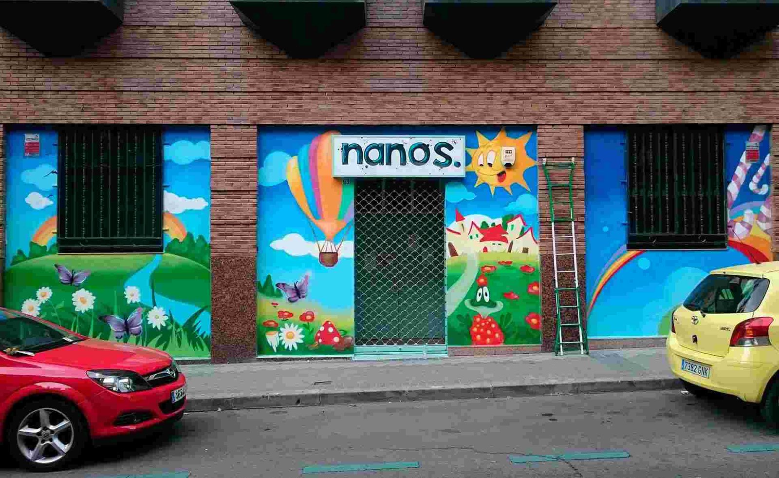 Mural infantil en guardería Nanos con globos, sol, campo y colores alegres