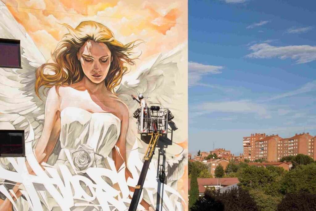 Mural institucional con ángel y lettering graffiti en fachada pública de Madrid
