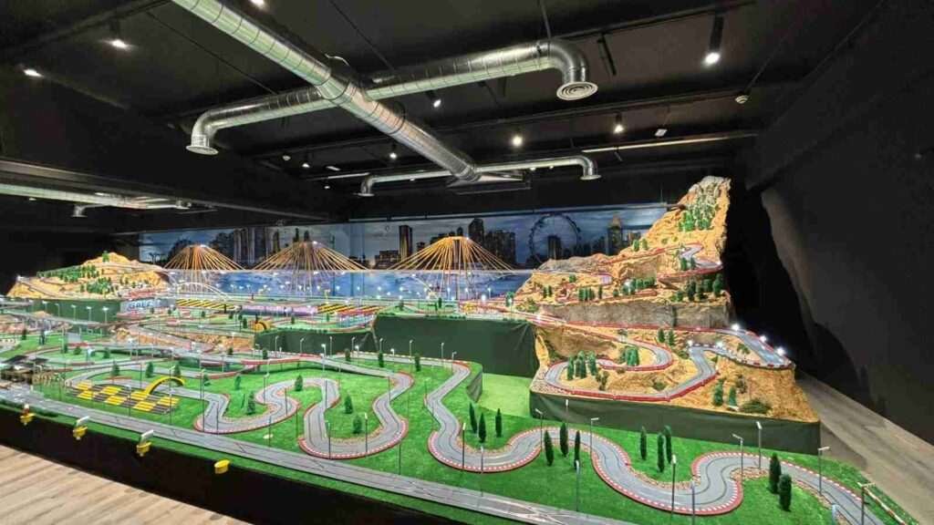Mural interior de Scalextric para GALA Autoescuela con puentes amarillos y skyline urbano