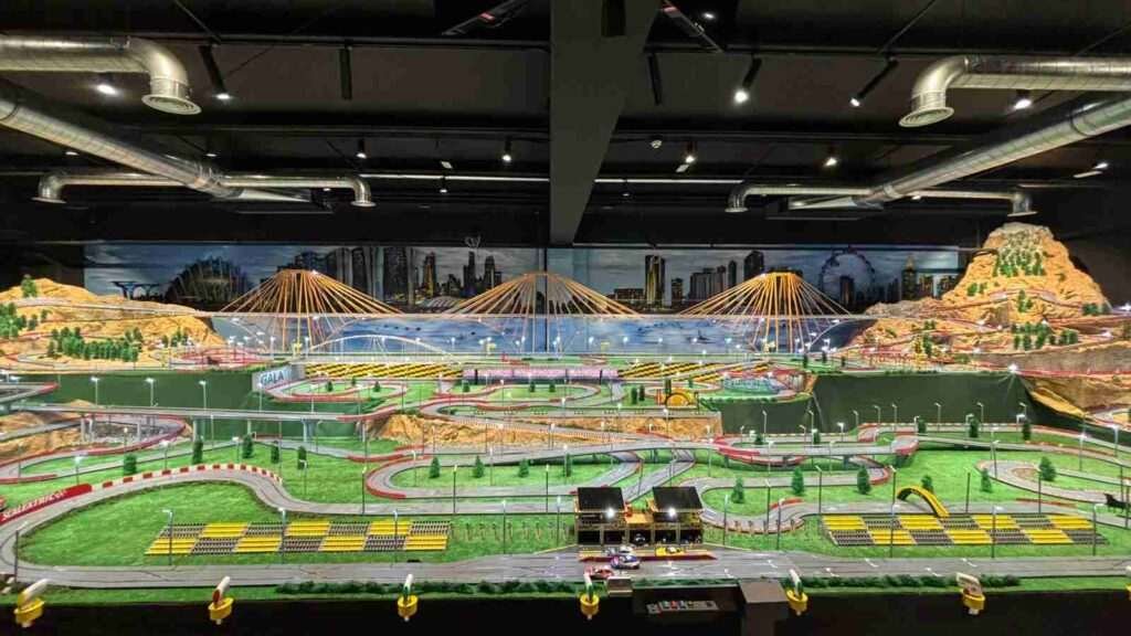 Vista frontal del mural interior para GALA Autoescuela con maqueta Scalextric y paisaje urbano