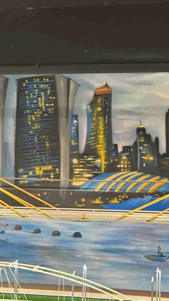 Skyline urbano pintado en el mural interior de GALA Autoescuela para ambientar la zona Scalextric