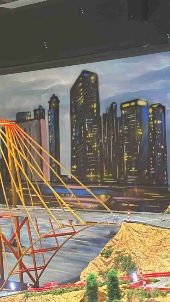 Primer plano del mural de paisaje urbano con puente y circuito Scalextric en oficinas GALA Autoescuela