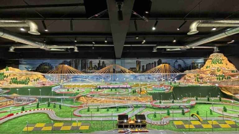 Vista completa de la maqueta Scalextric con mural de paisaje urbano en oficinas de GALA Autoescuela
