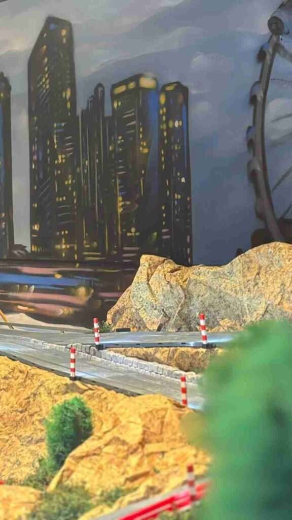 Detalle del mural interior de GALA Autoescuela con ciudad nocturna, rocas y circuito Scalextric