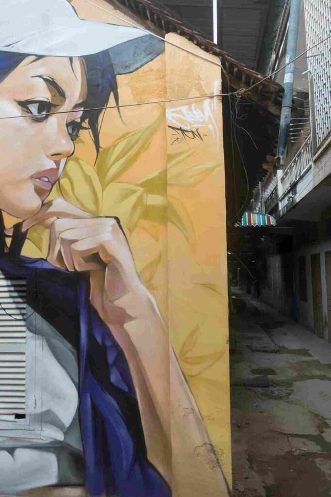 Mural graffiti en fachada de Camboya, retrato femenino con gorra para S’art Urban Art Festival.