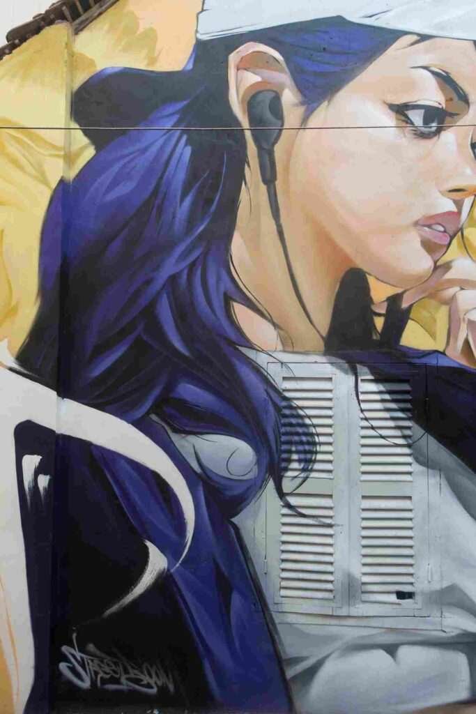 Mural graffiti en fachada de Camboya, retrato femenino con gorra para S’art Urban Art Festival.