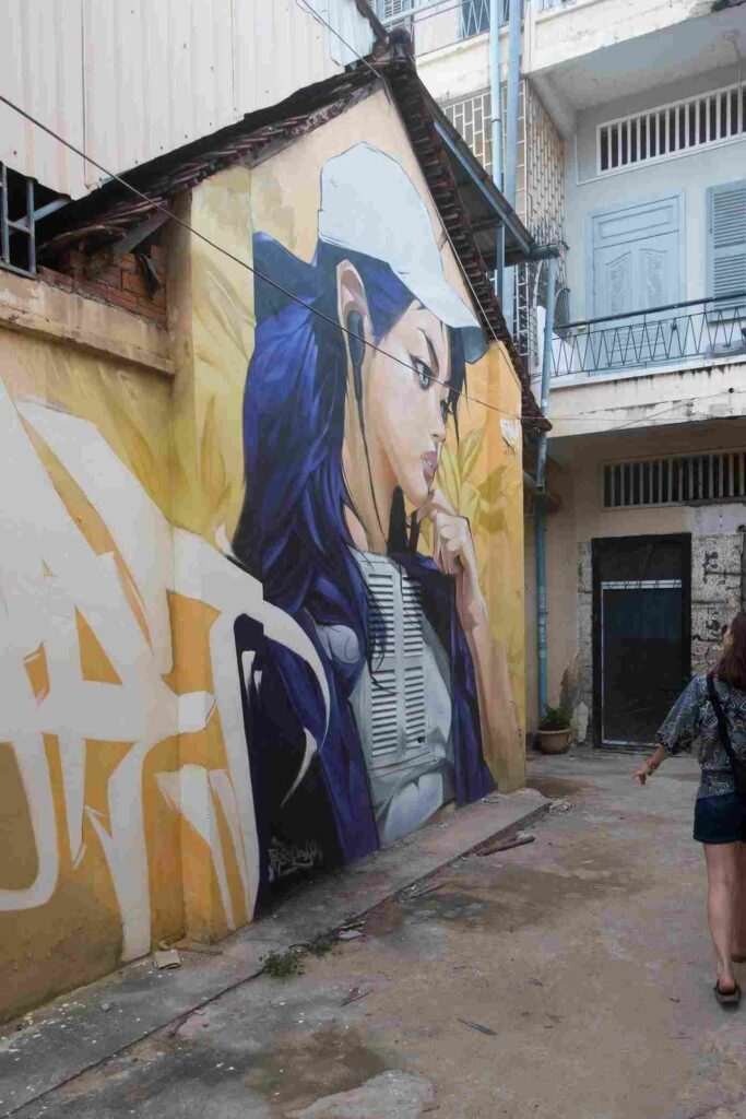 Mural graffiti en fachada de Camboya, retrato femenino con gorra para S’art Urban Art Festival.