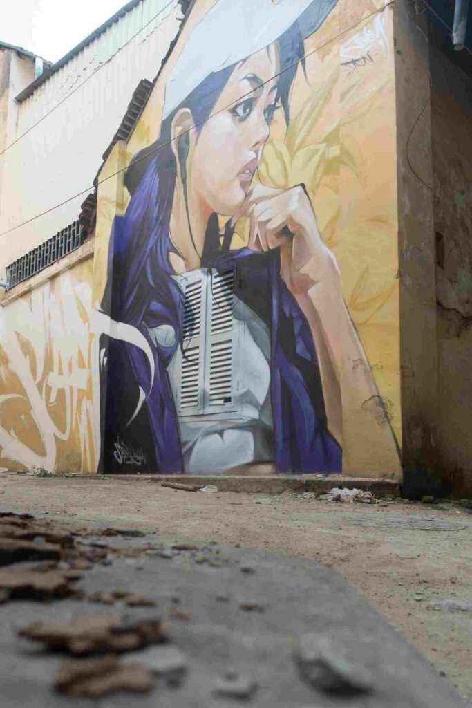 Mural graffiti en fachada de Camboya, retrato femenino con gorra para S’art Urban Art Festival.