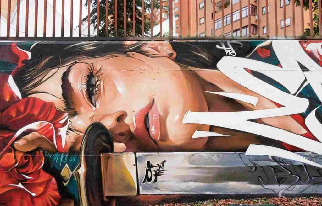 mural madrid the edge of the blade retrato femenino con rosas y serpiente tipografía graffiti blanca barrio del pilar