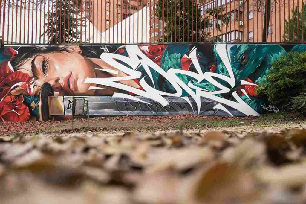 mural madrid the edge of the blade retrato femenino con rosas y serpiente tipografía graffiti blanca barrio del pilar