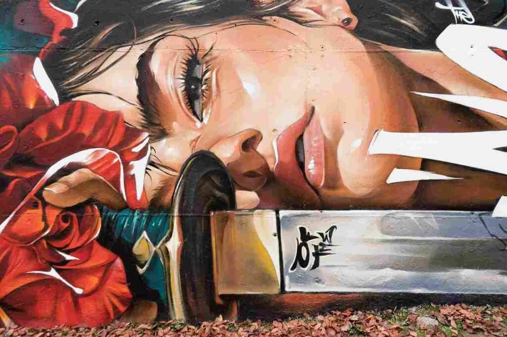 mural madrid the edge of the blade retrato femenino con rosas y serpiente tipografía graffiti blanca barrio del pilar