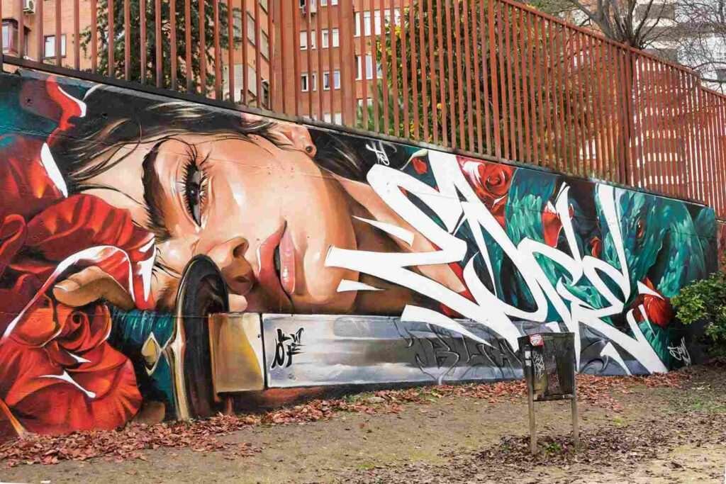mural madrid the edge of the blade retrato femenino con rosas y serpiente tipografía graffiti blanca barrio del pilar