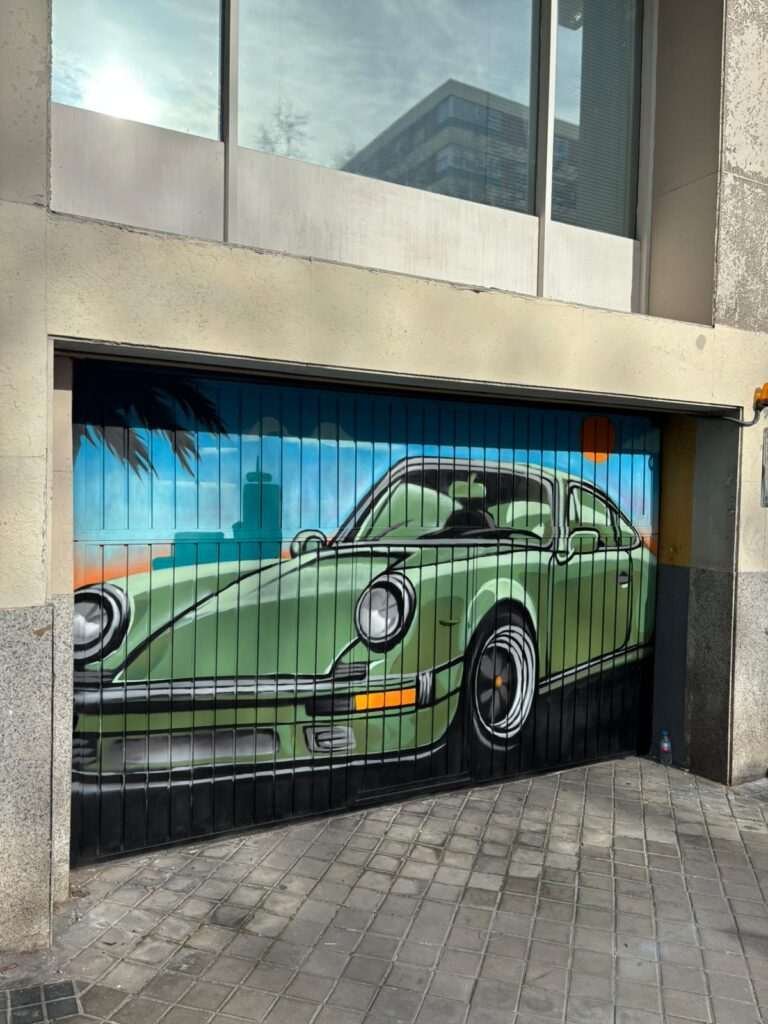 Vista frontal de cierre de garaje pintado con mural de coche clásico para comunidad de vecinos
