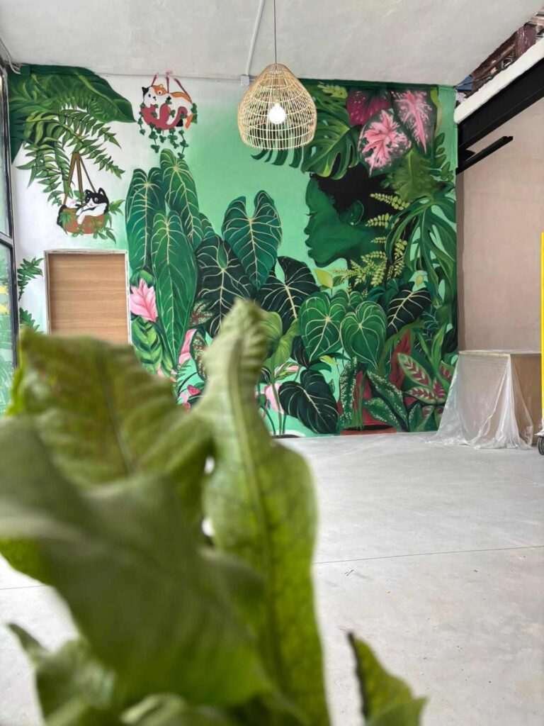 Mural interior de temática tropical en Torrelavega con gran pared vegetal y lámpara decorativa