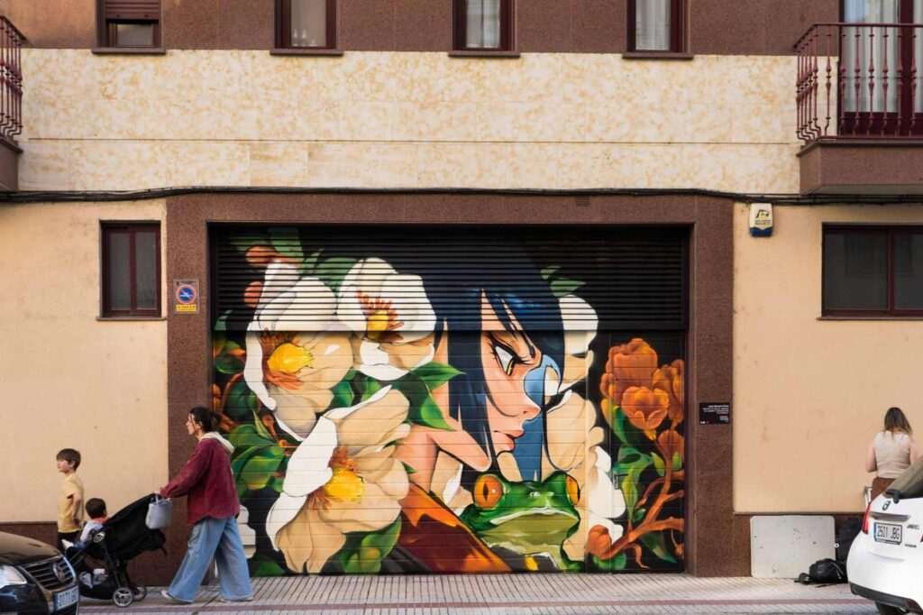 Mural ganador en una puerta de garaje del Barrio del Oeste de Salamanca, con princesa, rana y flores