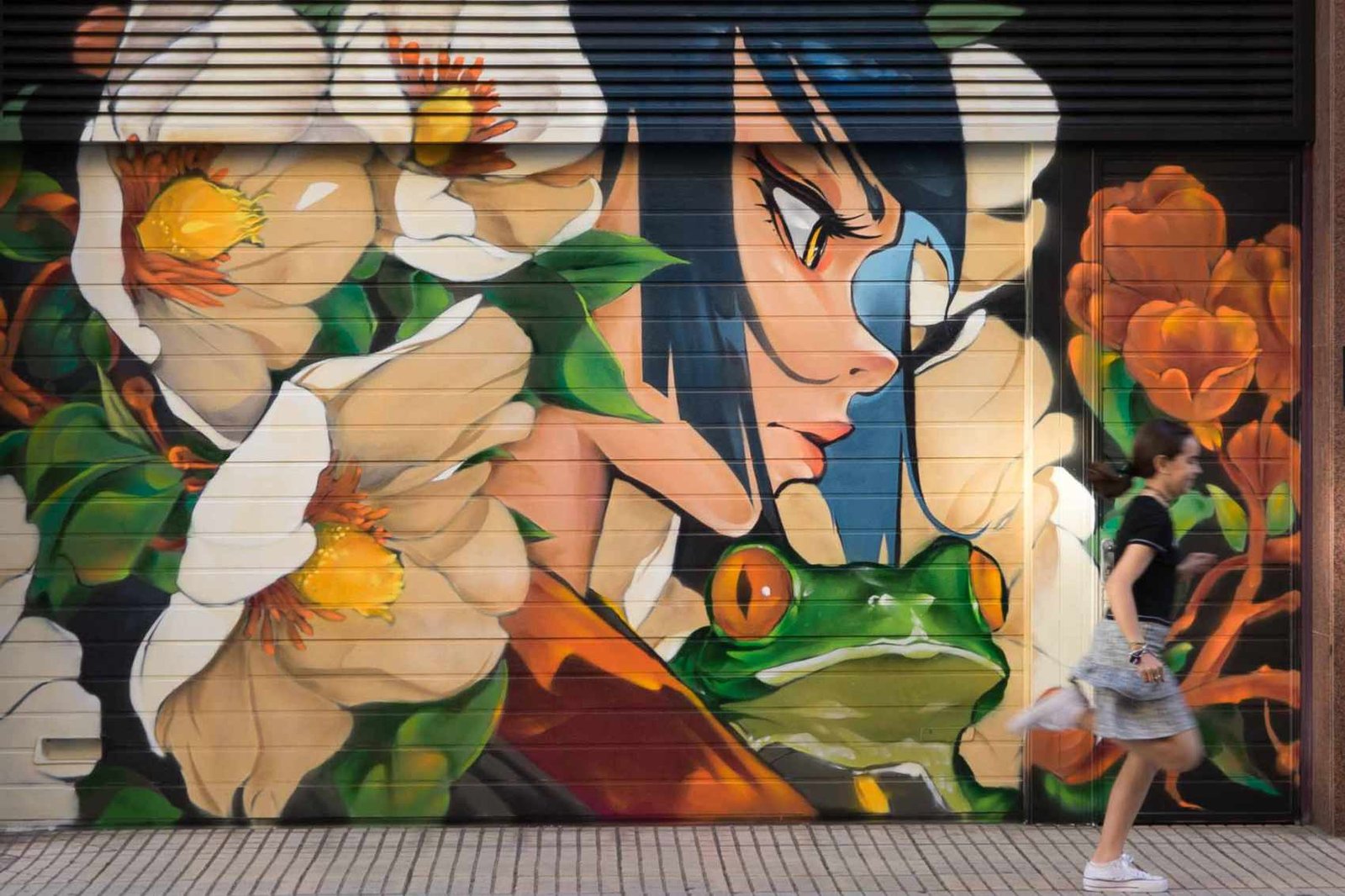 Mural de arte urbano en el Barrio del Oeste de Salamanca con figura femenina, rana y composición floral