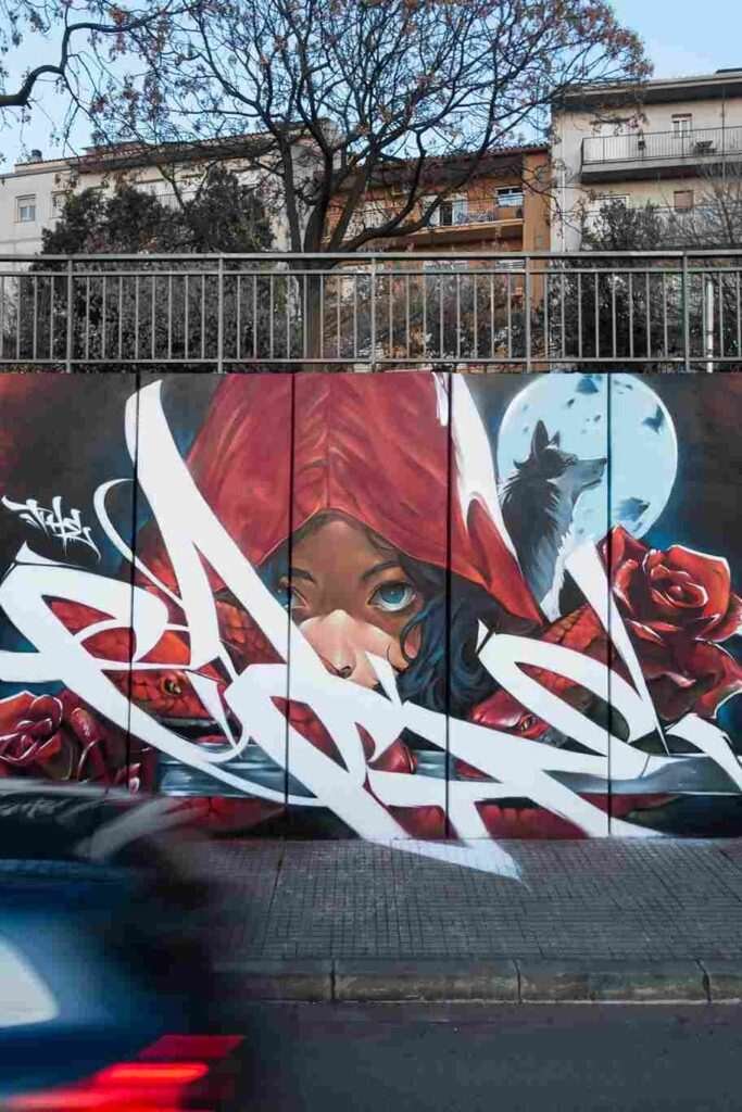 Mural de arte urbano con Caperucita Roja, lobo, serpientes y rosas rojas en Cataluña
