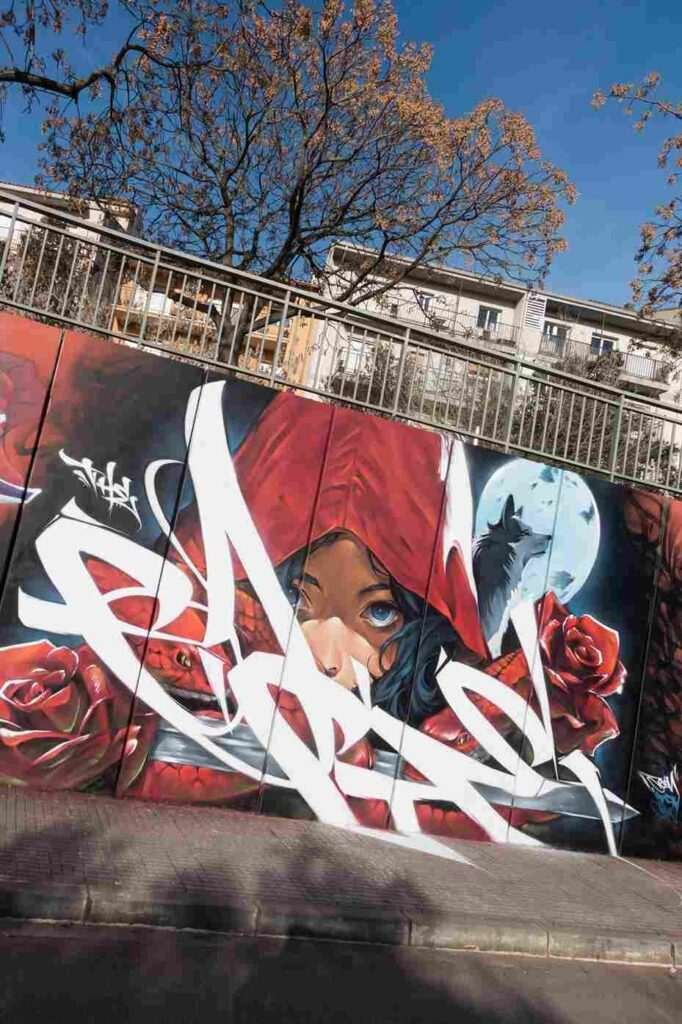 Primer plano de La Caputxeta Vermella con capucha roja en un mural graffiti exterior