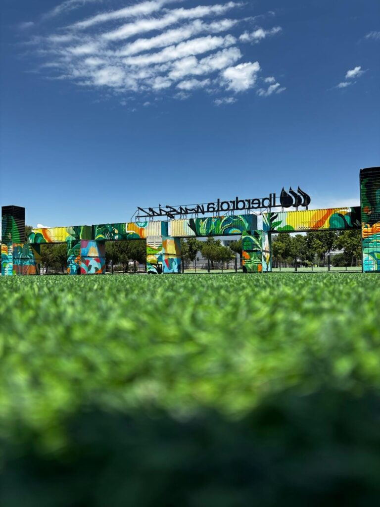 Trasera del acceso de Iberdrola Music con mural selva sobre las torres de contenedores