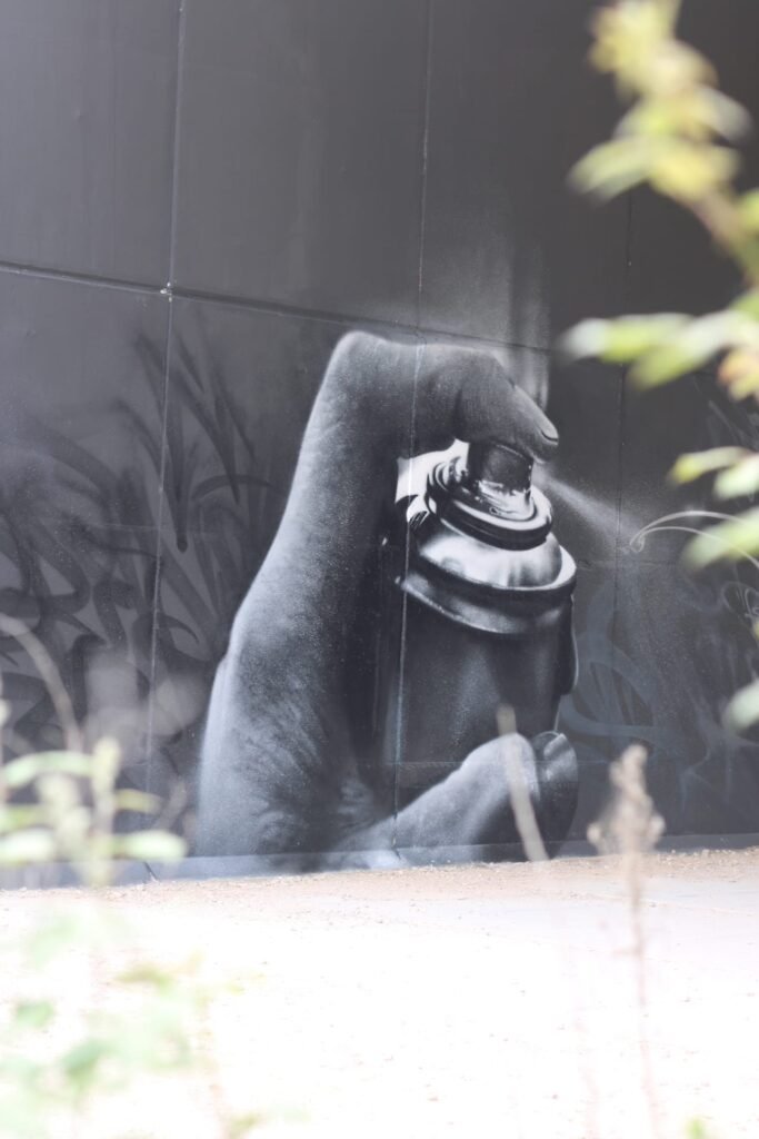 Primer plano de la mano fotorrealista y el bote de spray pintados sobre el muro
