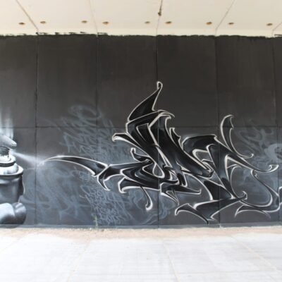 Graffiti realista en blanco y negro con una mano sosteniendo un spray, en Madrid Norte