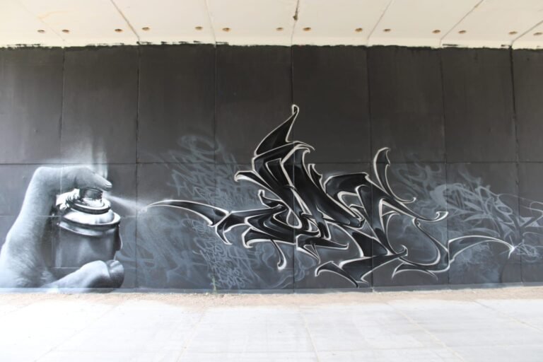 Graffiti realista en blanco y negro con una mano sosteniendo un spray, en Madrid Norte