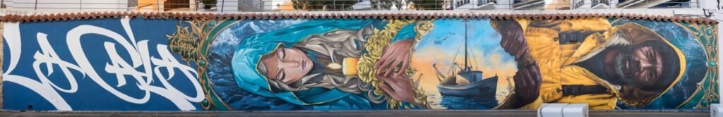Vista completa del mural «La Cala»: lettering, Mare de Déu de la Candelera, barca de pesca y pescador